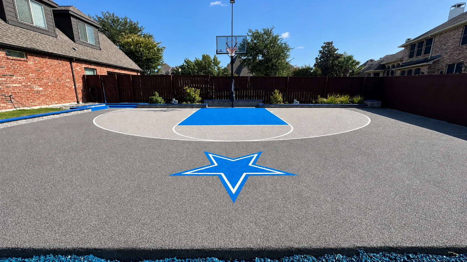 Custom grey residential basketball court with a blue star graphic