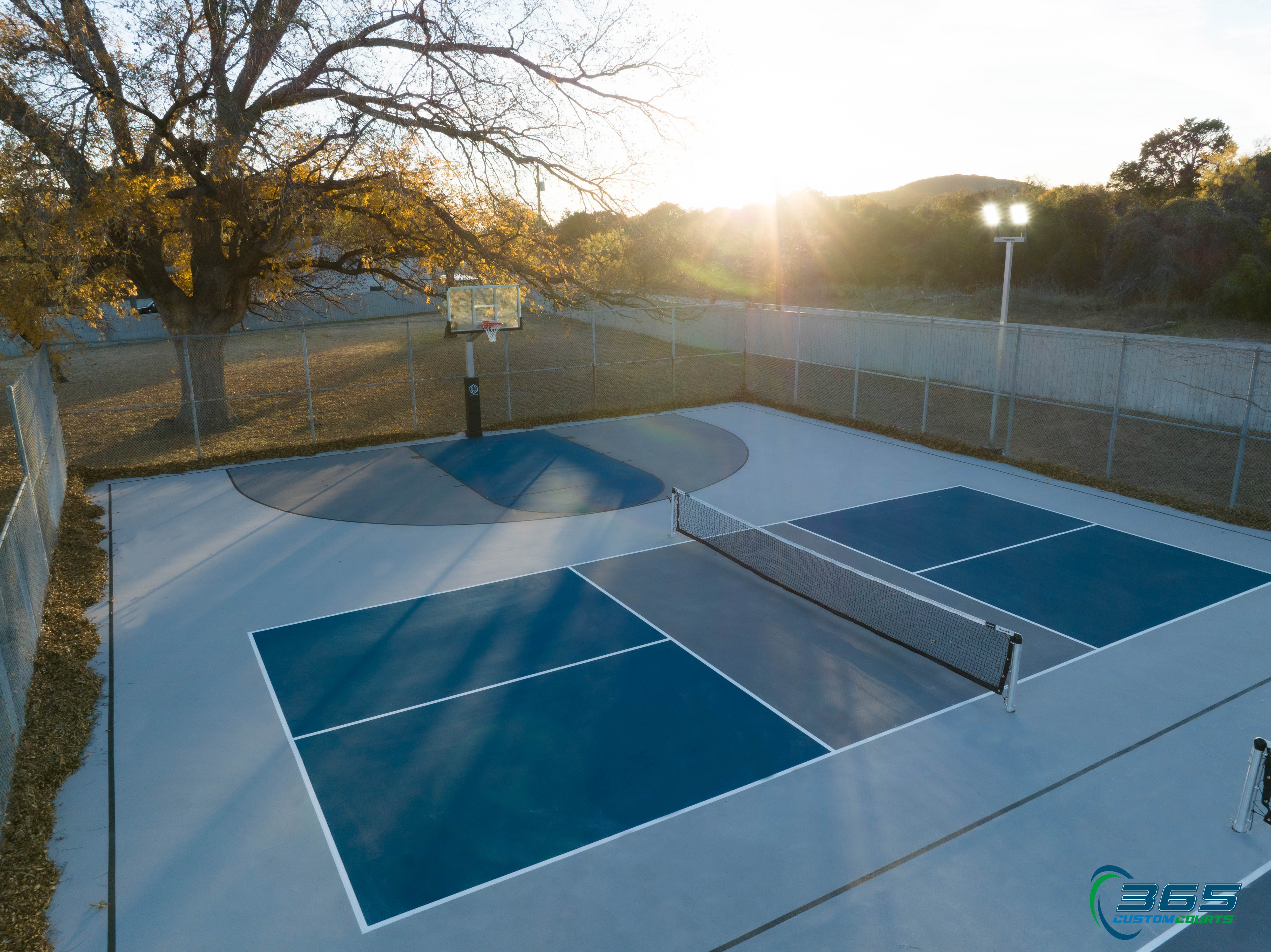 Aerial view of a custom blue multi-sport court beside a lake
