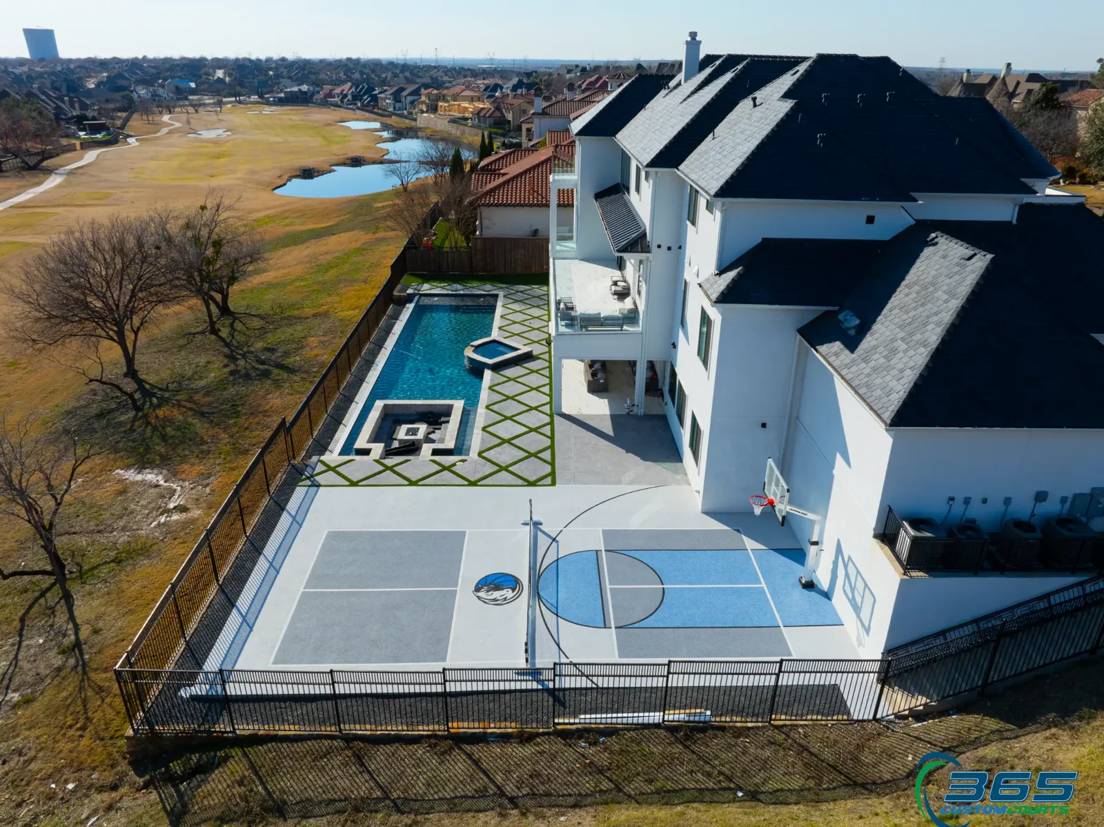 Aerial view of a grey multi-sport court beside a pool and golf course