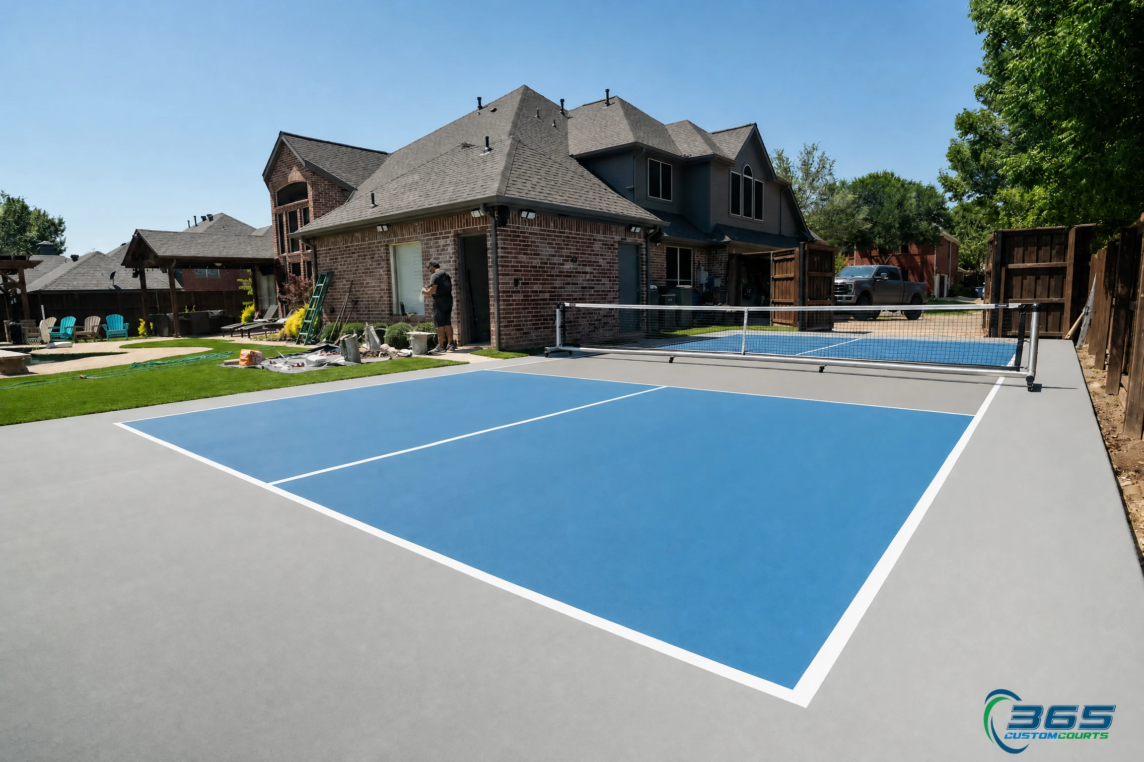 Blue residential pickleball court with net beside a custom DFW home
