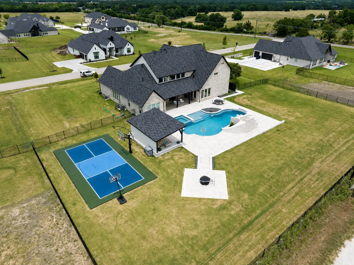 Aerial view of a large estate with a compact blue basketball court and pool