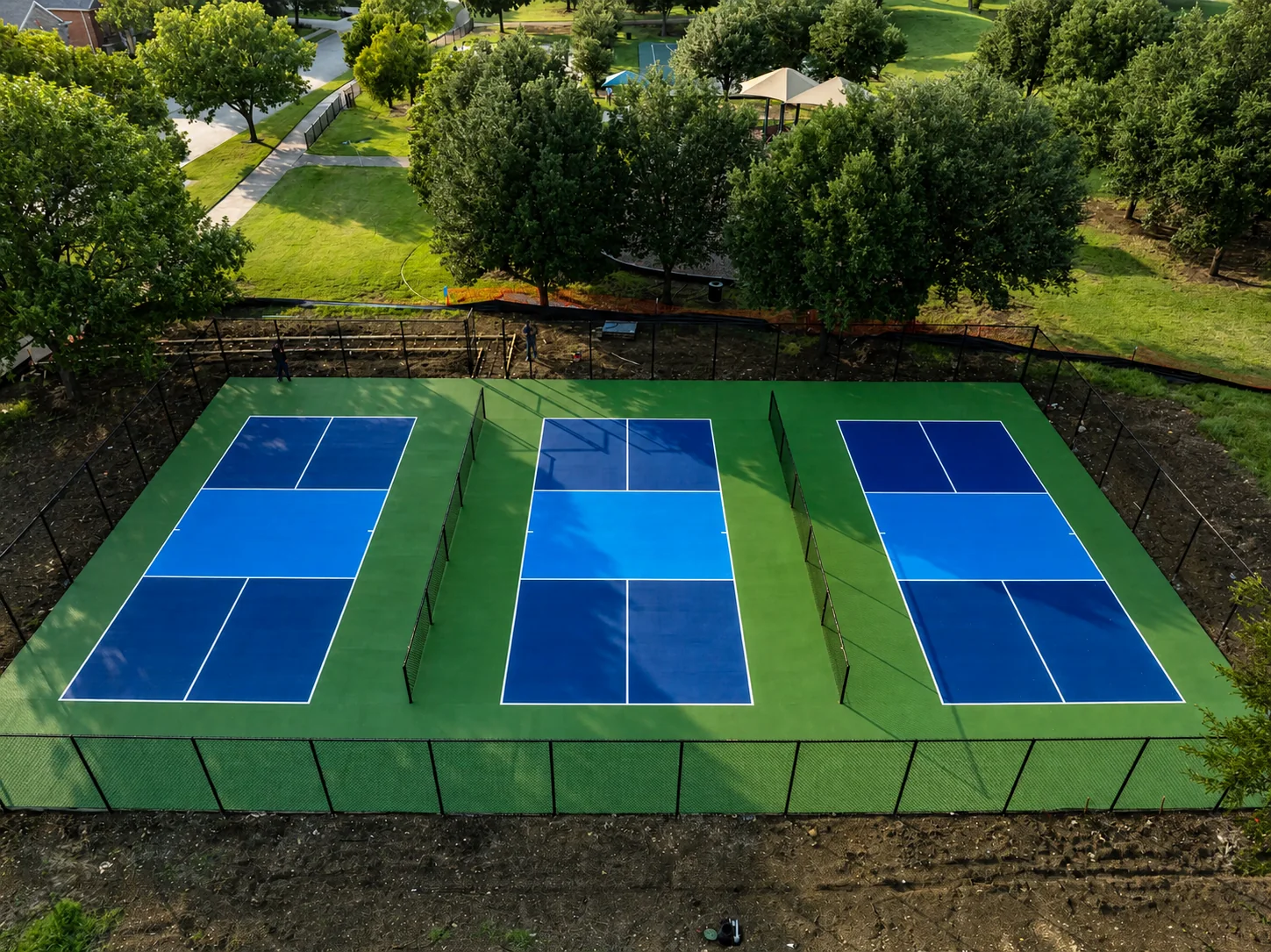 Aerial view of four fenced blue-and-green pickleball courts