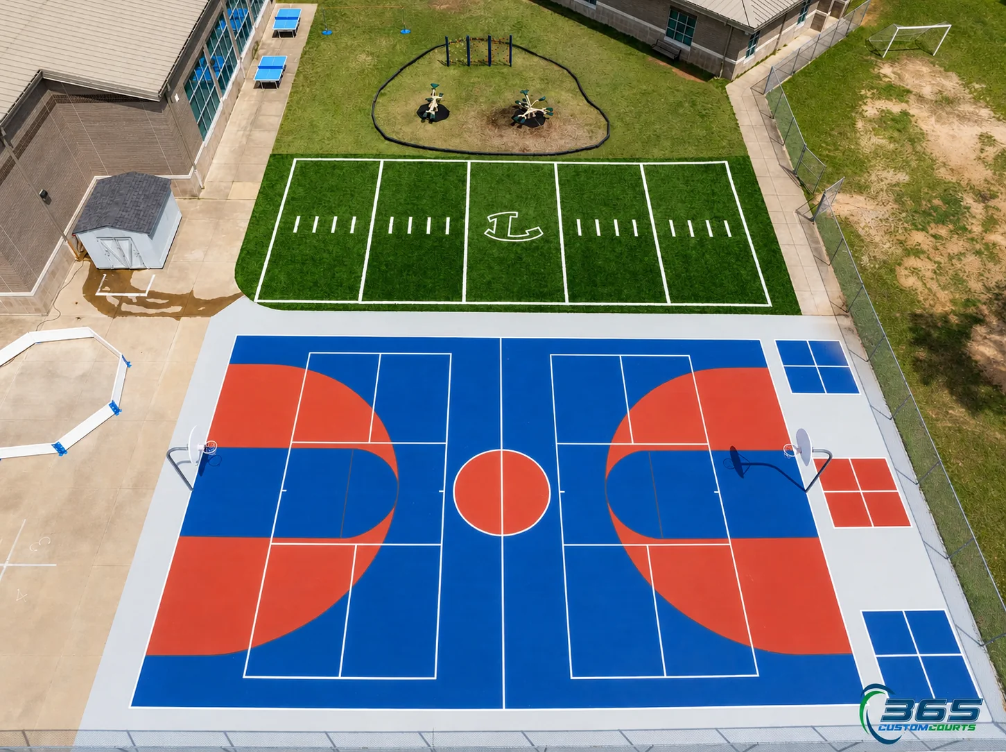 Aerial view of a school basketball court and adjacent artificial-turf football field